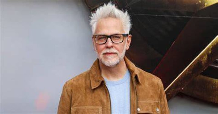 A serious-looking James Gunn superimposed over a dark-hued image of Superman from the 'Suicide Squad: Kill the Justice League' game