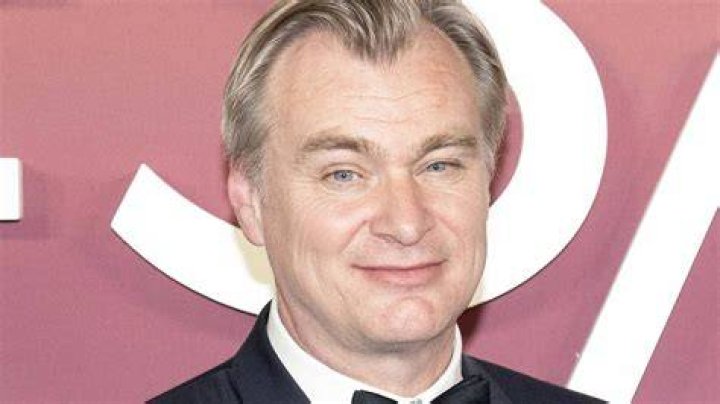 Christopher Nolan wears a light gray suit and a black tie at the 'Oppenheimer' premiere at Cinema Le Grand Rex in 2023.