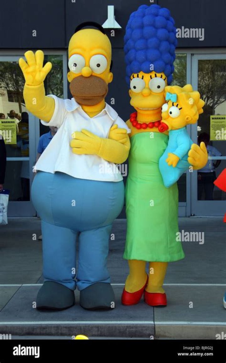 Homer, Marge, and Maggie are holding on to the Empire State Building. 