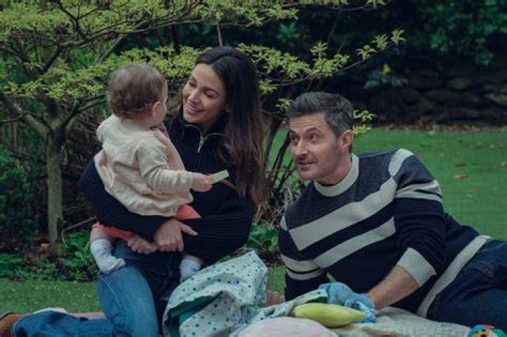 Maya (Michelle Keegan) and Joe Burkett (Richard Armitage) smile and play with their young daughter Lily in Netflix's Fool Me Once. 