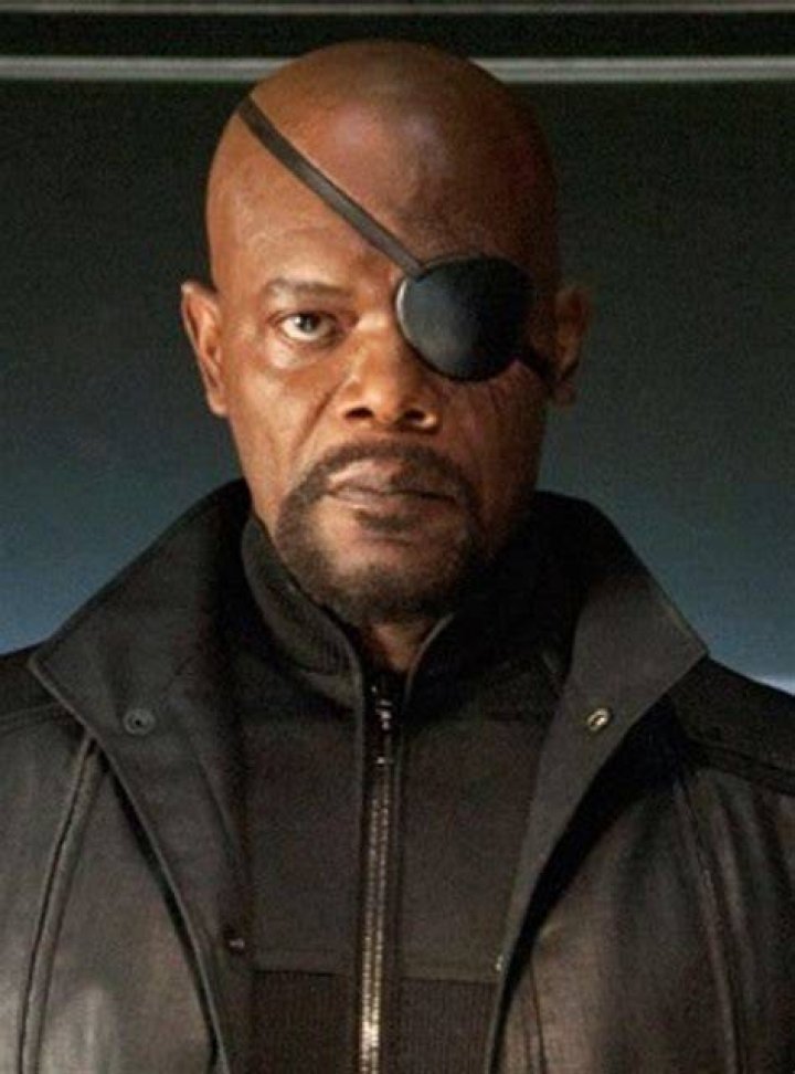 Nick Fury is looking up and standing in front of a fire exit. 